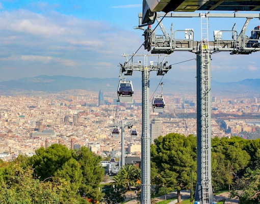 Cable car ascending Montjuic Hill with panoramic view of Barcelona cityscape.