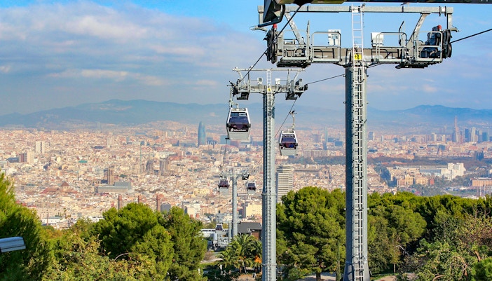 Cable car ascending Montjuic Hill with panoramic view of Barcelona cityscape.