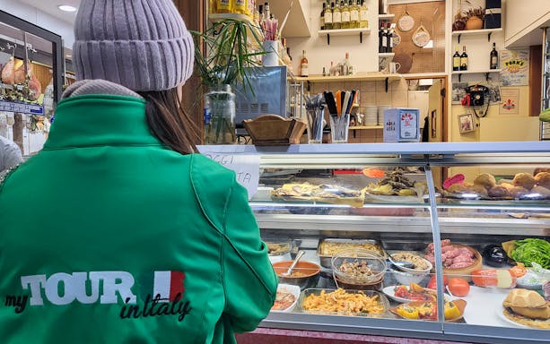 Customer at deli counter during guided food tour in Florence, Italy.