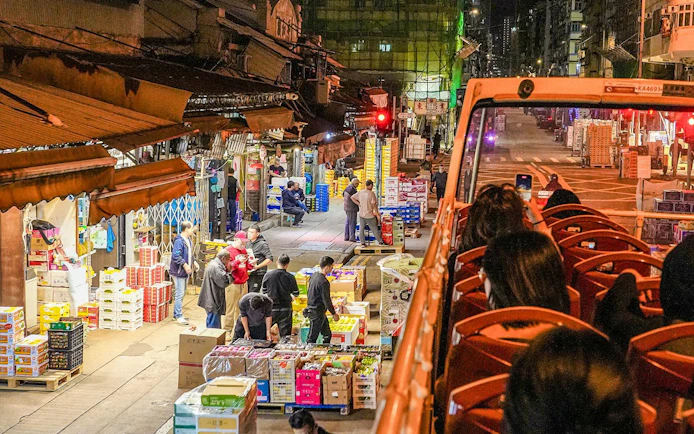 Open-top bus passing through Kowloon night market, Hong Kong.