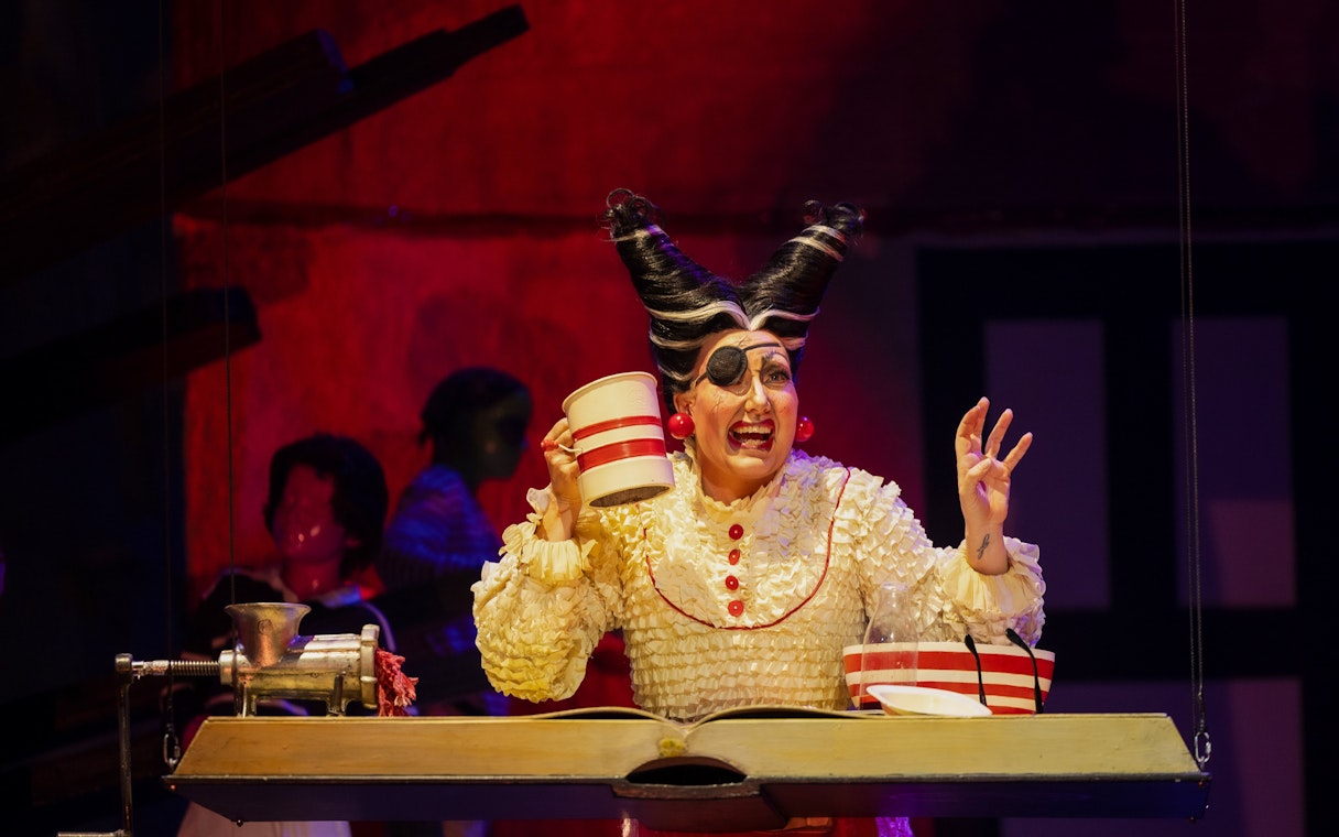 Performer in costume during Hansel and Gretel stage show, holding a mug.