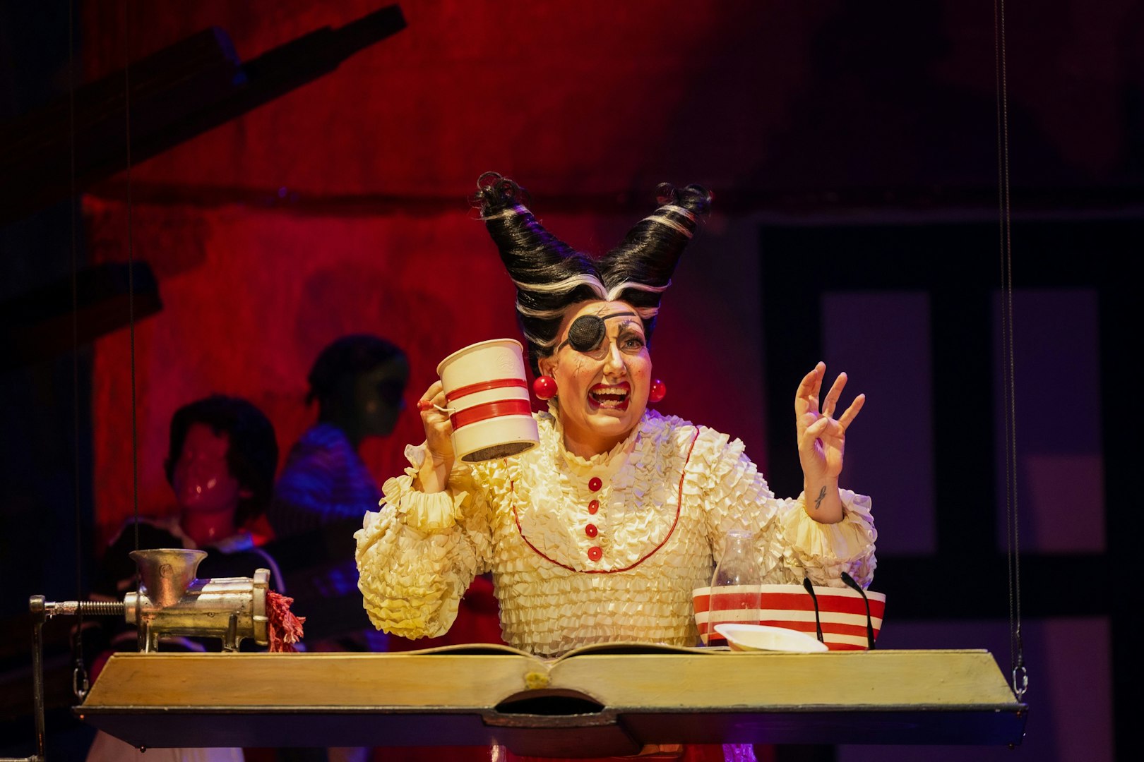 Performer in costume during Hansel and Gretel stage show, holding a mug.