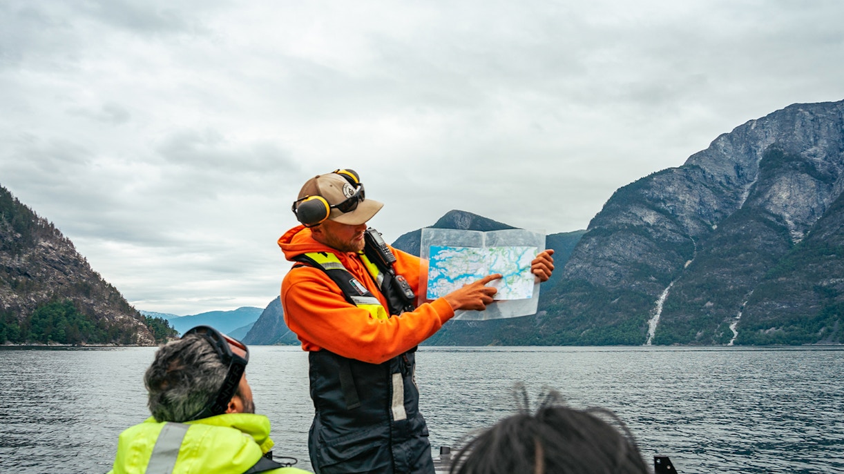 Guide showing map during high-speed Loch Ness cruise with mountains in background.