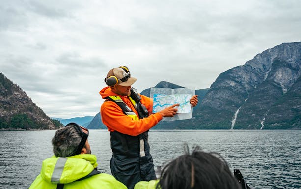 Guide showing map during high-speed Loch Ness cruise with mountains in background.