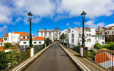 Old stone arch bridge leading to white buildings in Nordeste, Sao Miguel, Azores.