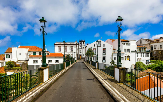 Old stone arch bridge leading to white buildings in Nordeste, Sao Miguel, Azores.