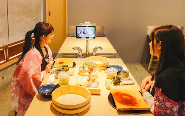 Friends making sushi in chef attire near Tokyo Tower.