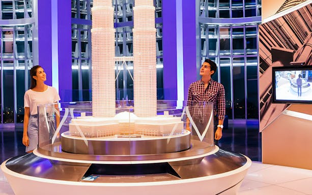 Visitors admire a model of the Petronas Twin Towers during an evening tour in Kuala Lumpur.