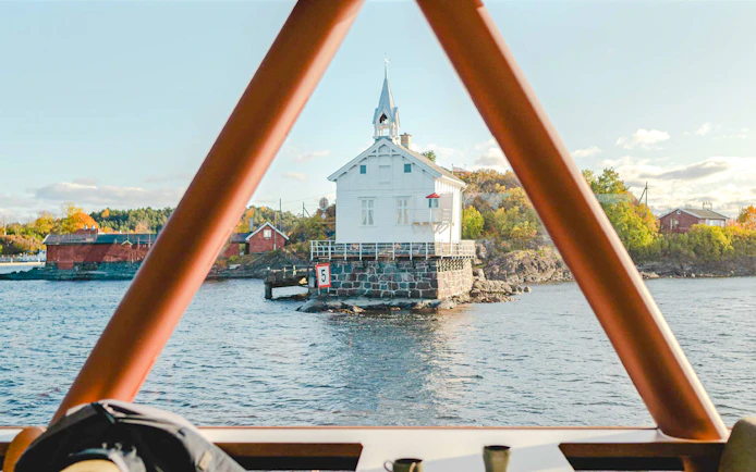 White lighthouse on a rocky islet viewed from a boat during an Oslo fjord cruise.