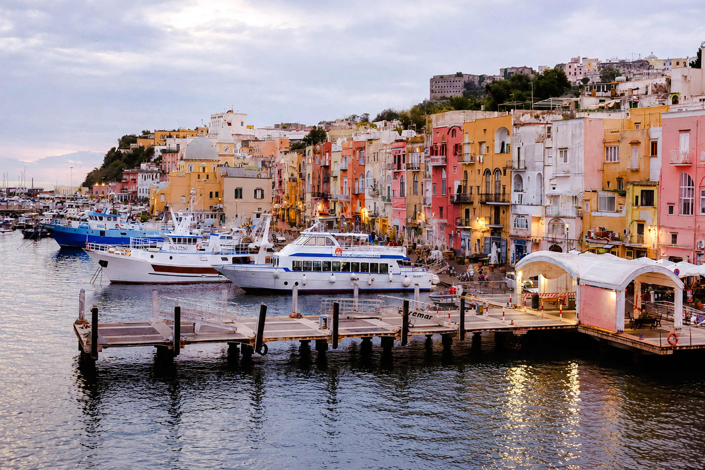 Boats docked at colorful Procida harbor, part of the Procida Boat Tour from Ischia with lunch, Naples.
