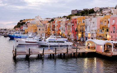 Boats docked at colorful Procida harbor, part of the Procida Boat Tour from Ischia with lunch, Naples.