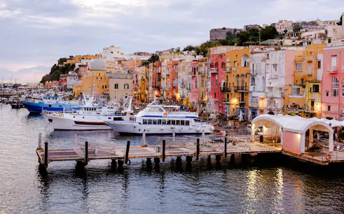 Boats docked at colorful Procida harbor, part of the Procida Boat Tour from Ischia with lunch, Naples.