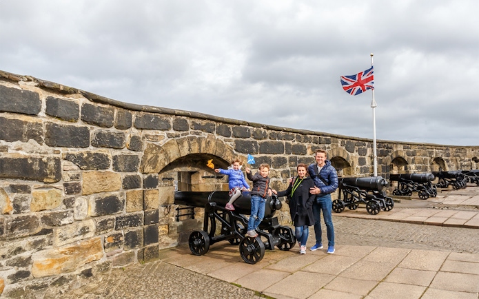 Family exploring Edinburgh Castle courtyard, Scotland.
