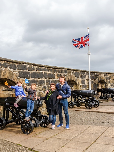 Family exploring Edinburgh Castle courtyard, Scotland.