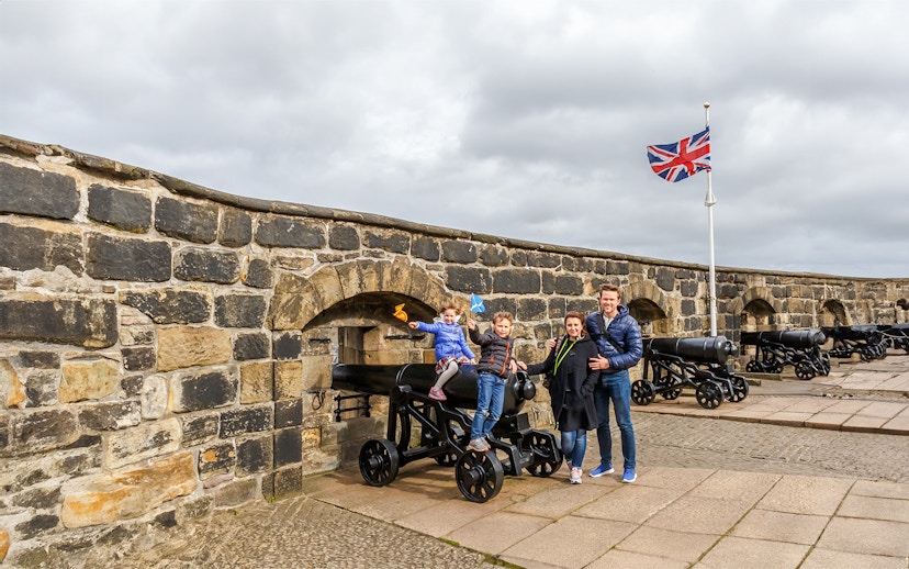 Family exploring Edinburgh Castle courtyard, Scotland.