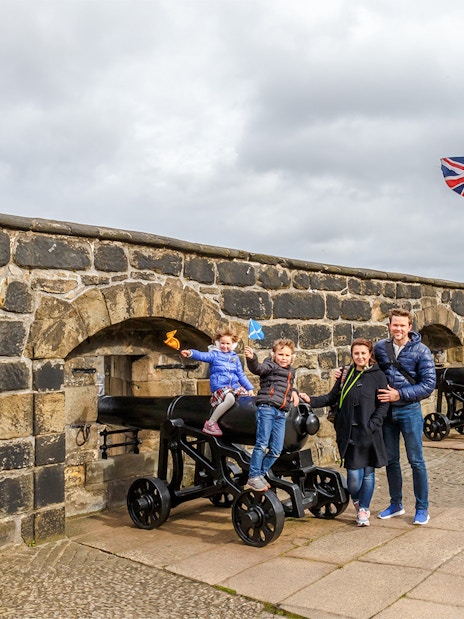 Family exploring Edinburgh Castle courtyard, Scotland.