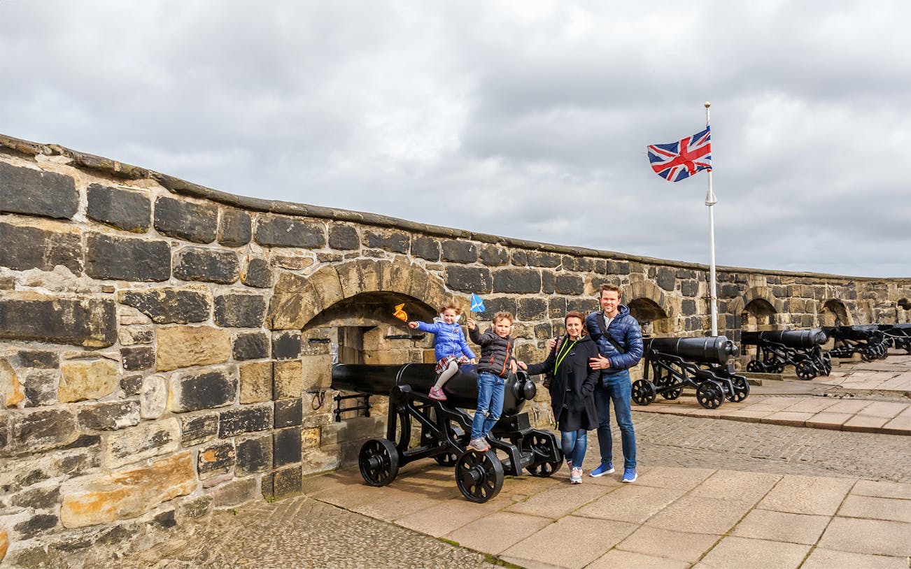 Family exploring Edinburgh Castle courtyard, Scotland.