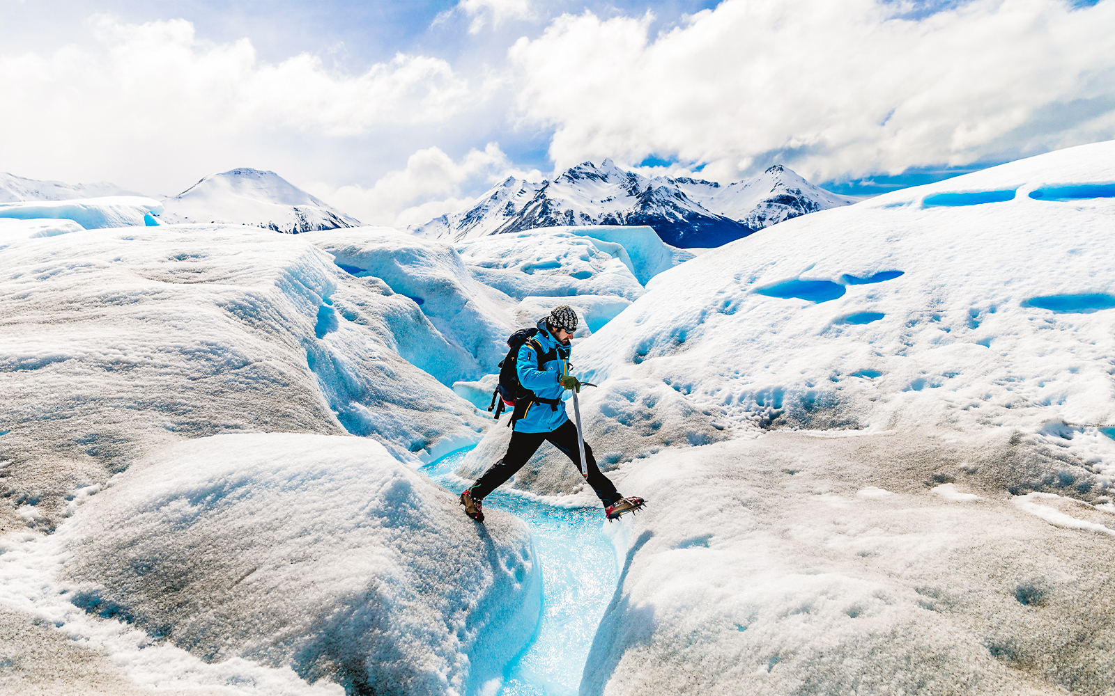 Tourist leaping over ice caves at Big Ice, Perito Moreno Glacier, Argentina.