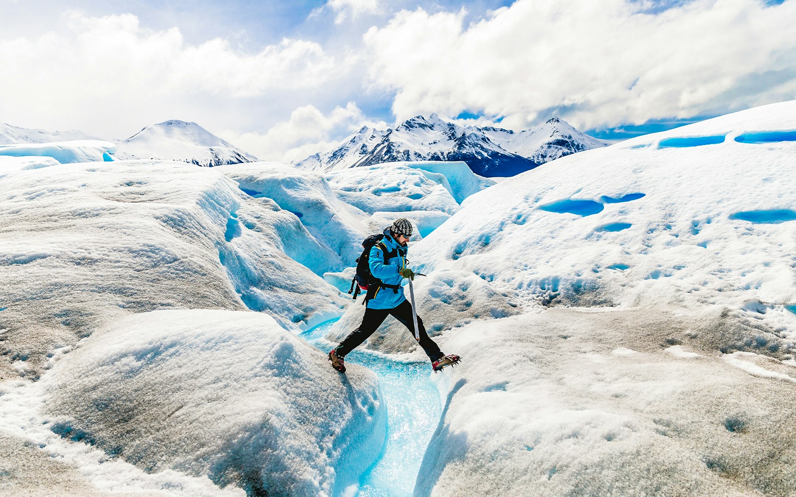 Tourist leaping over ice caves at Big Ice, Perito Moreno Glacier, Argentina.