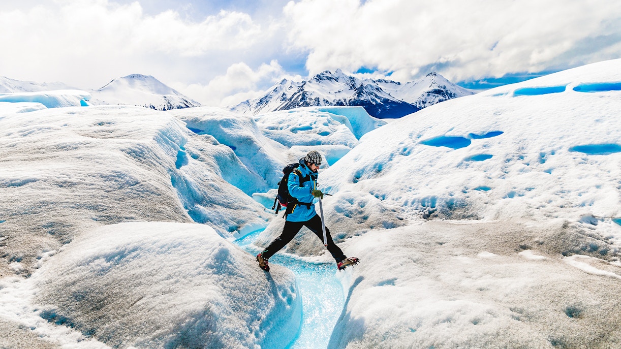Tourist leaping over ice caves at Big Ice, Perito Moreno Glacier, Argentina.