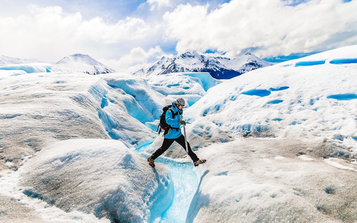 Tourist leaping over ice caves at Big Ice, Perito Moreno Glacier, Argentina.