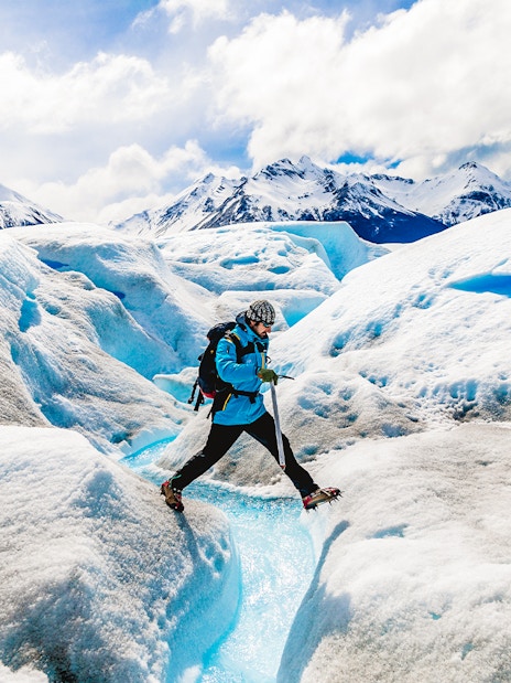 Tourist leaping over ice caves at Big Ice, Perito Moreno Glacier, Argentina.