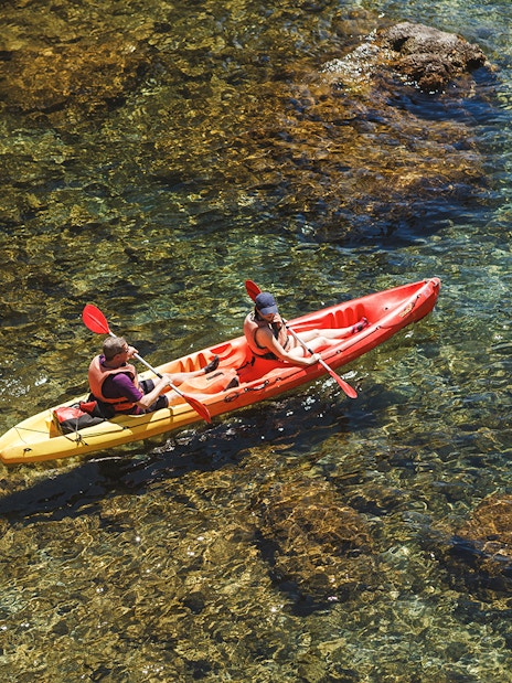 Kayakers paddling in clear waters near Dubrovnik at sunset.