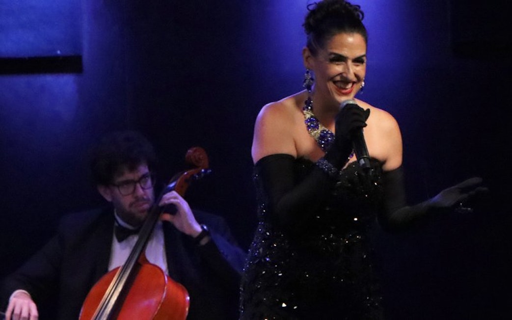 Singer performing at Michelangelo Tango Show with cellist in background.