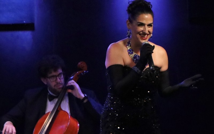 Singer performing at Michelangelo Tango Show with cellist in background.