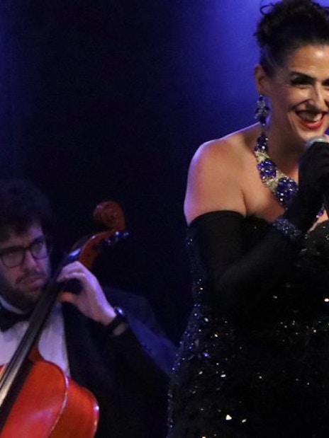 Singer performing at Michelangelo Tango Show with cellist in background.