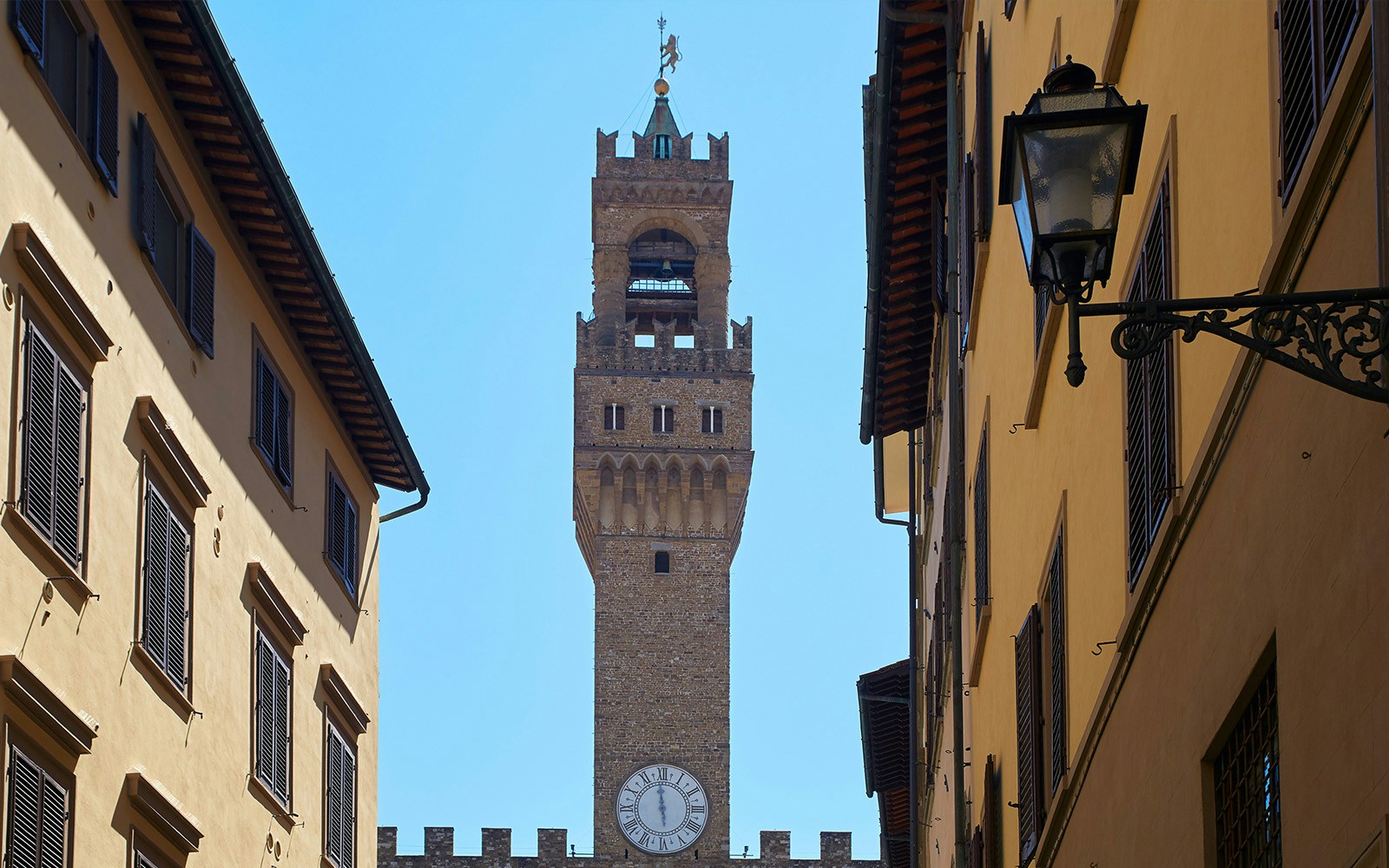 Palazzo Vecchio tower and spires framed by narrow Florence street.