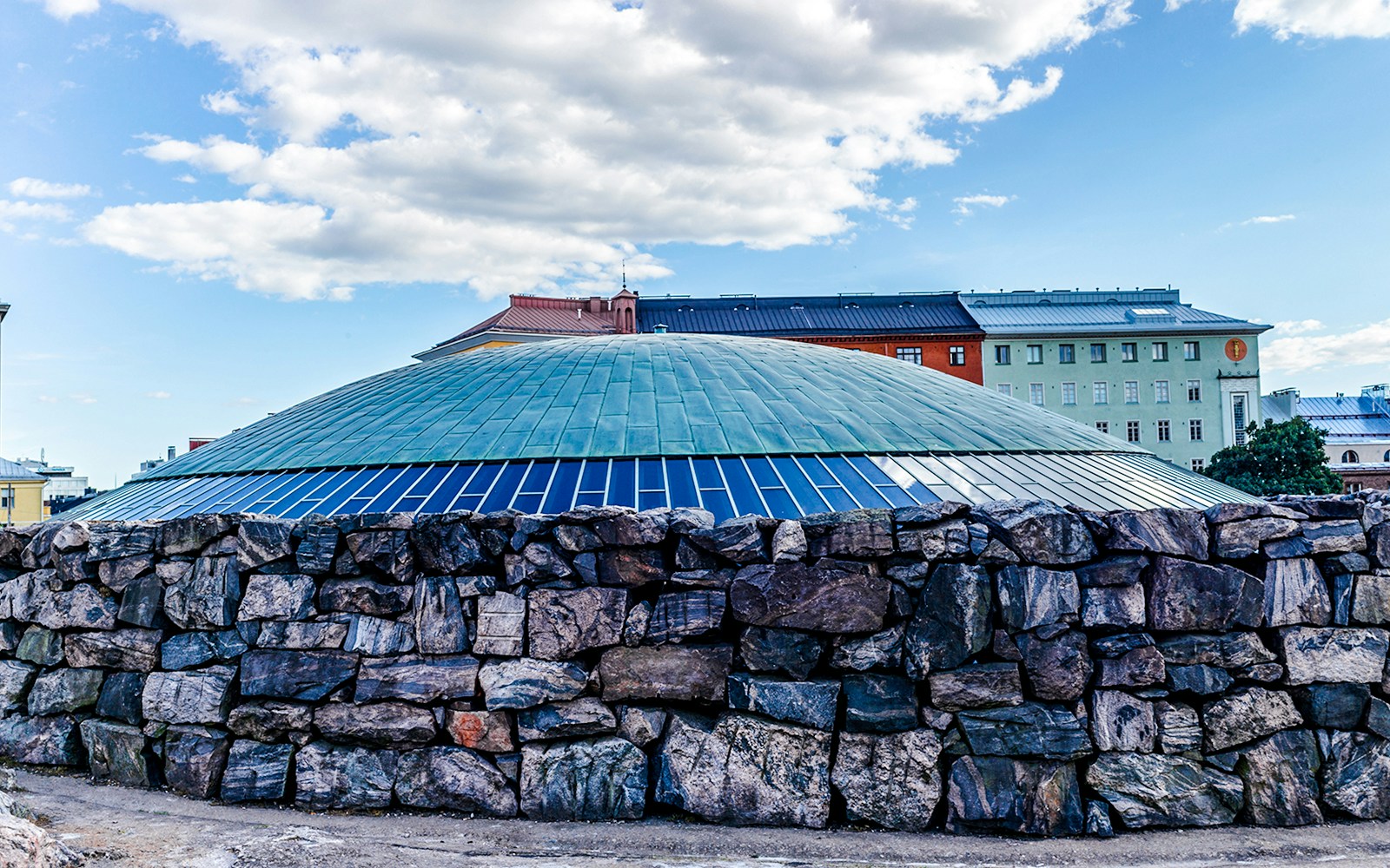 Cúpula da Igreja Temppeliaukio em Helsinque com parede de pedra e céu.