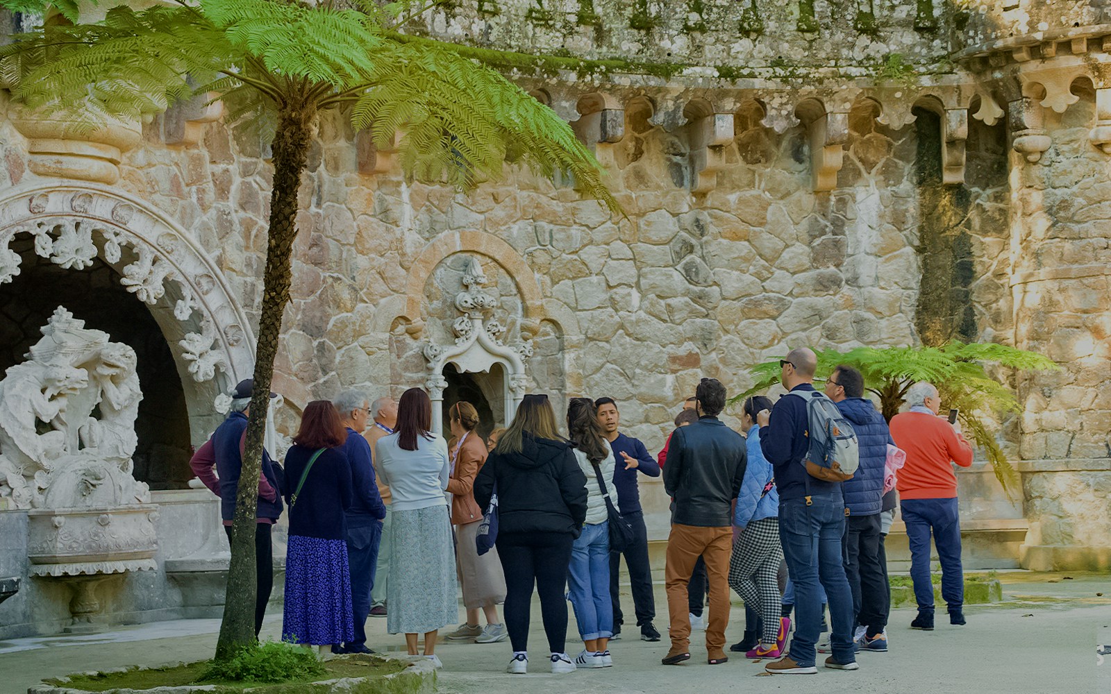 Guide discussing Quinta de Regaleira Palace history with tourists in Sintra, Portugal.