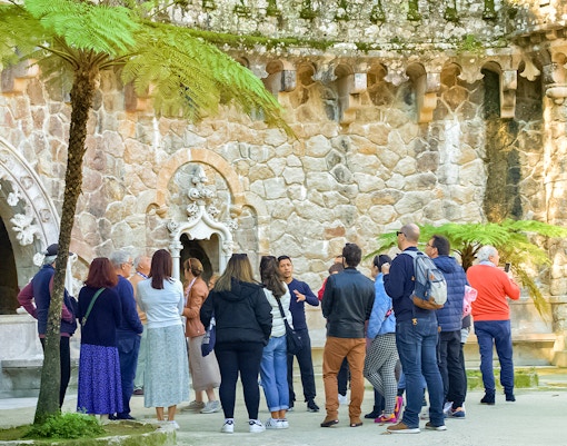 Guide discussing Quinta de Regaleira Palace history with tourists in Sintra, Portugal.