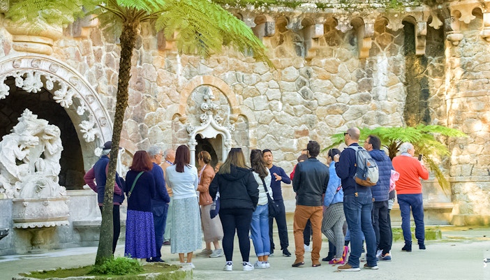 Guide discussing Quinta de Regaleira Palace history with tourists in Sintra, Portugal.
