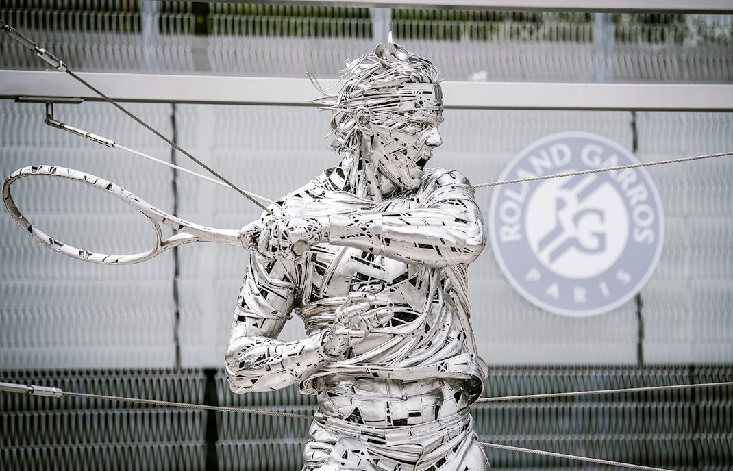 Roland Garros statue at Paris stadium entrance during guided tour.
