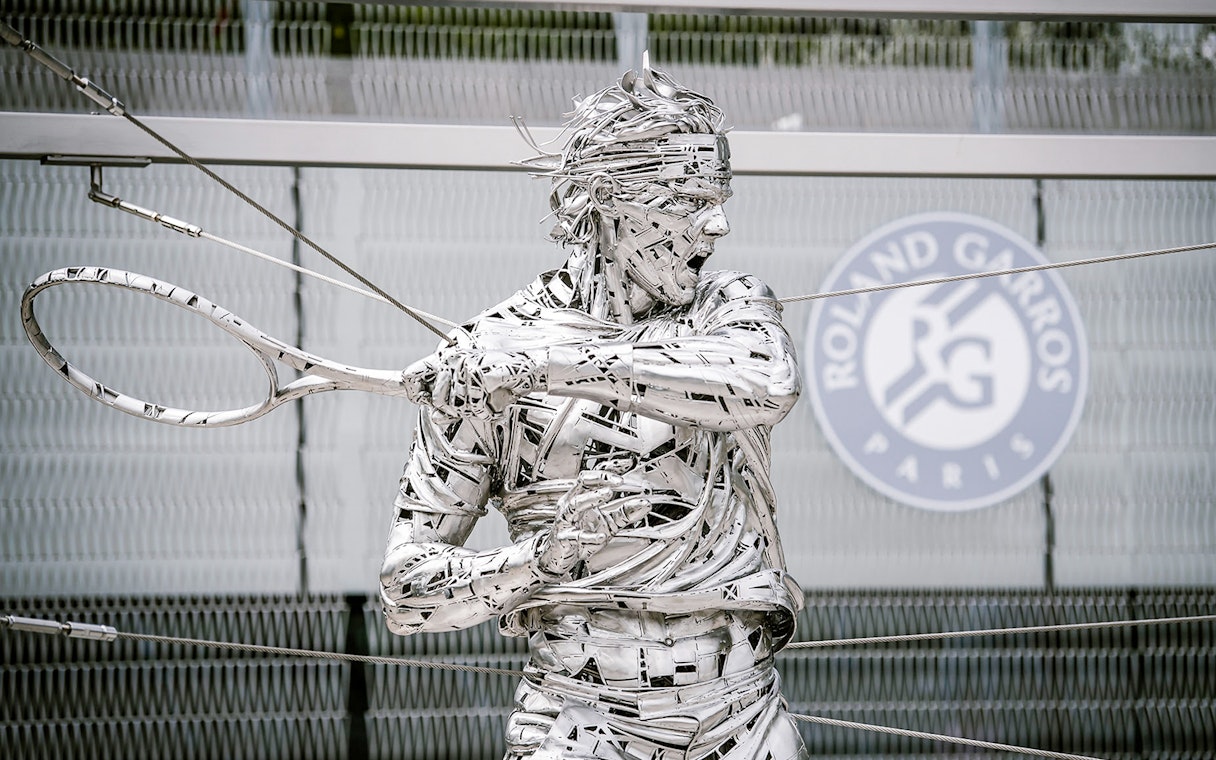Roland Garros statue at Paris stadium entrance during guided tour.