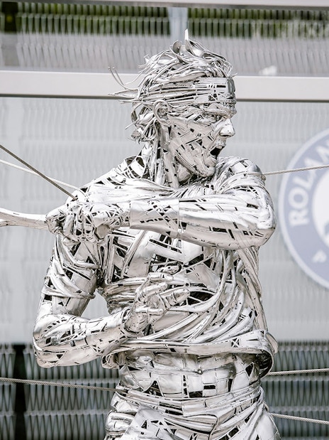 Roland Garros statue at Paris stadium entrance during guided tour.