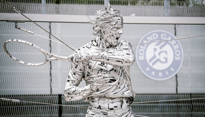 Roland Garros statue at Paris stadium entrance during guided tour.