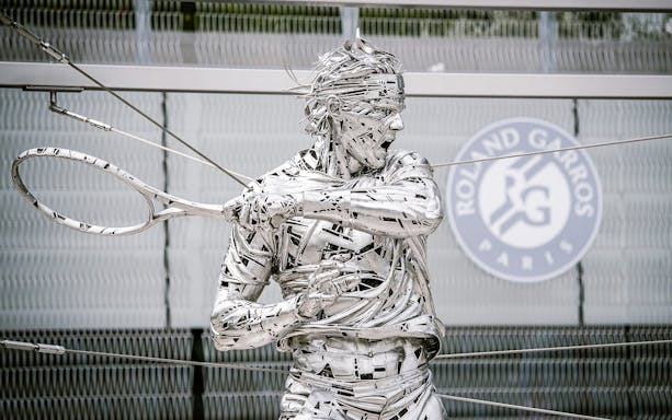 Roland Garros statue at Paris stadium entrance during guided tour.