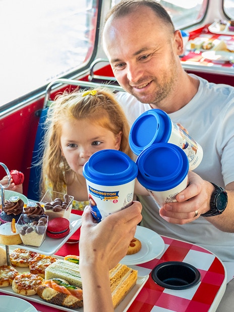 Guests enjoying afternoon tea on the Paddington Bus with sandwiches and pastries.
