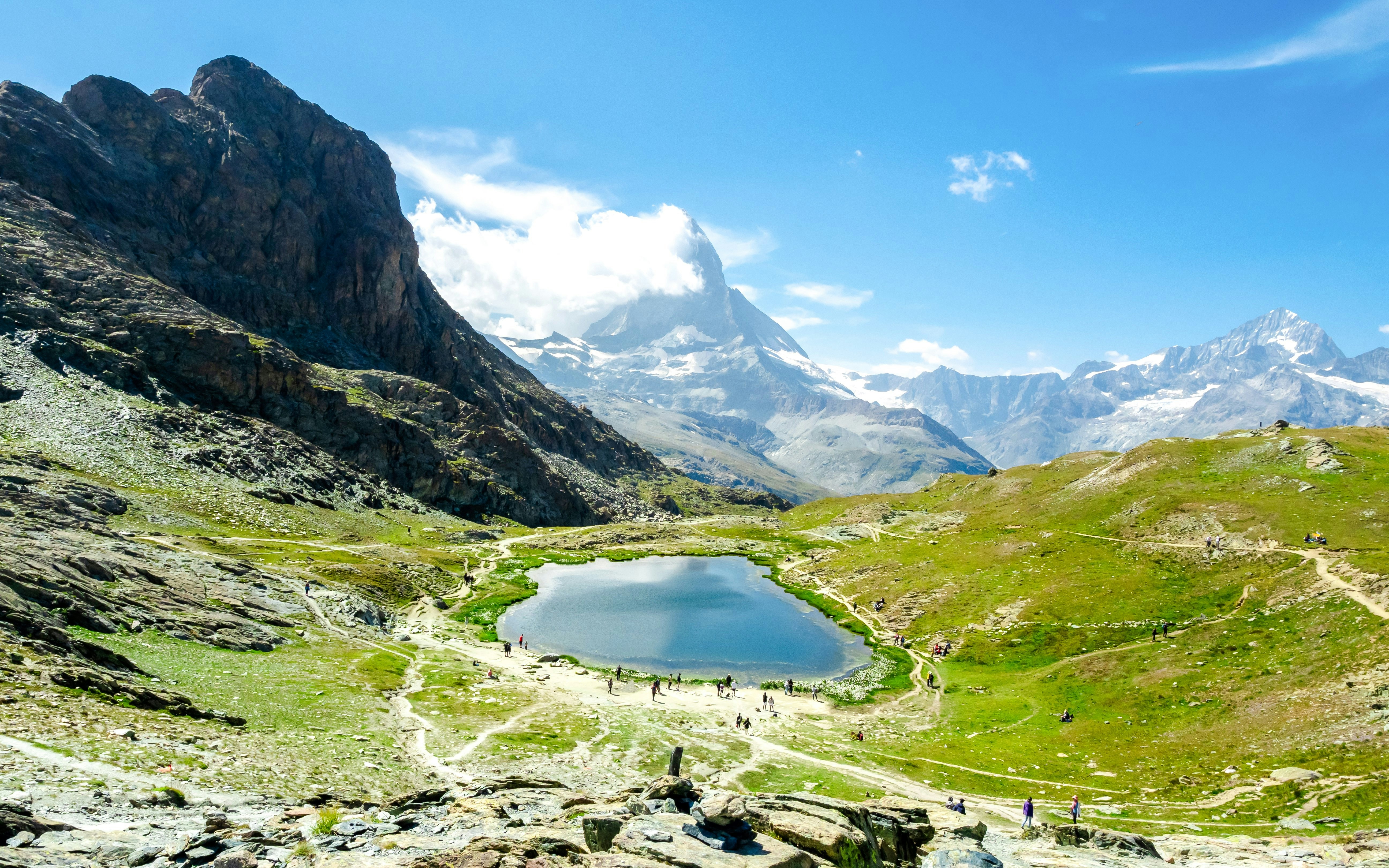 Mountain view from Riffelberg with a lake and hiking trails in the Swiss Alps.