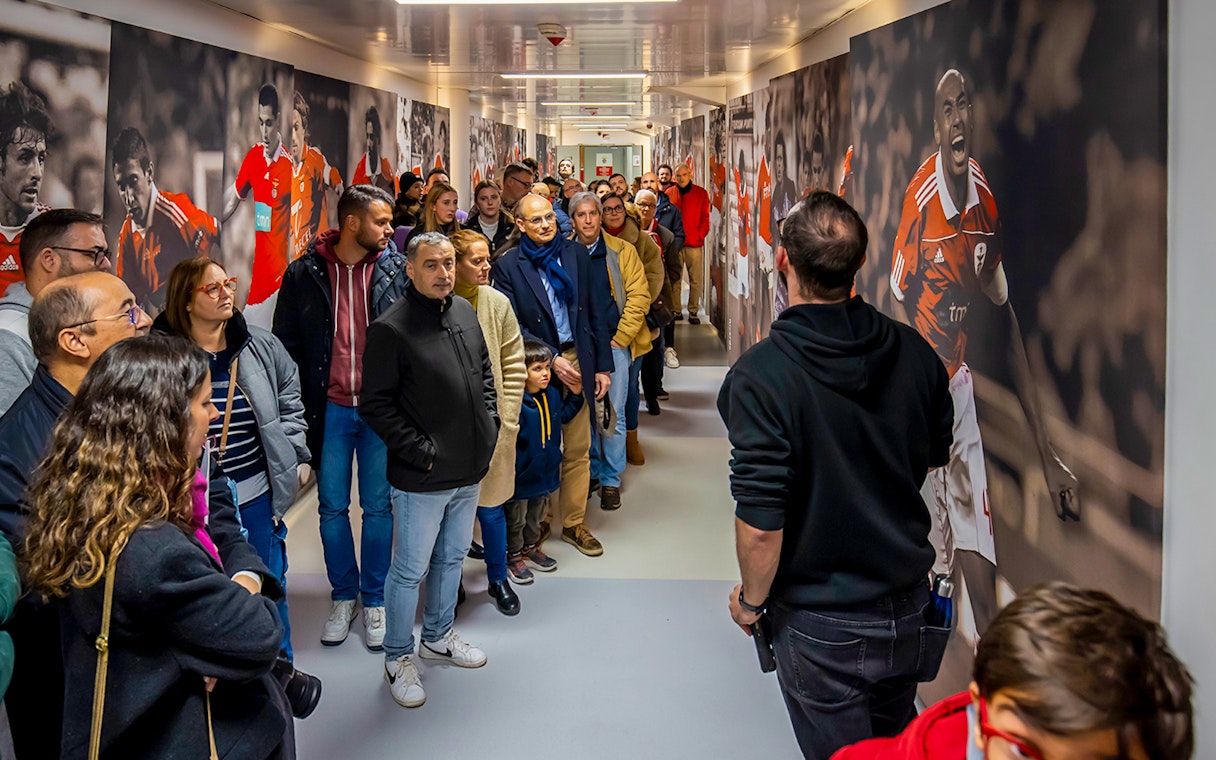 Visitors on a guided tour at Benfica Stadium museum hallway with player murals.