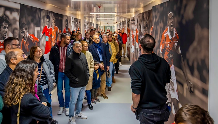 Visitors on a guided tour at Benfica Stadium museum hallway with player murals.