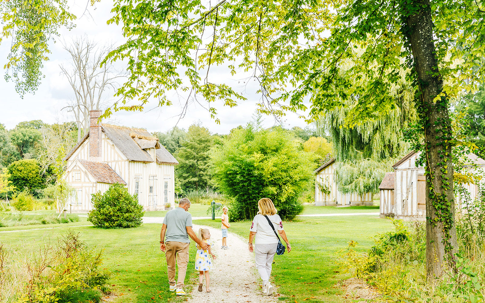 Family walking through gardens near Chateau of Chantilly, France.
