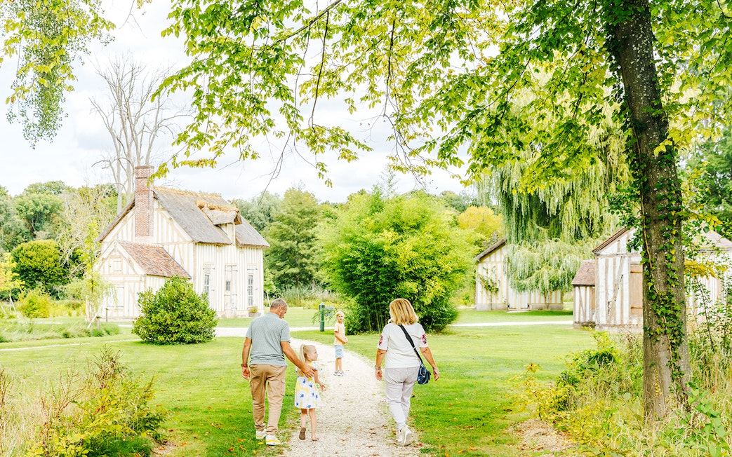 Family walking through gardens near Chateau of Chantilly, France.