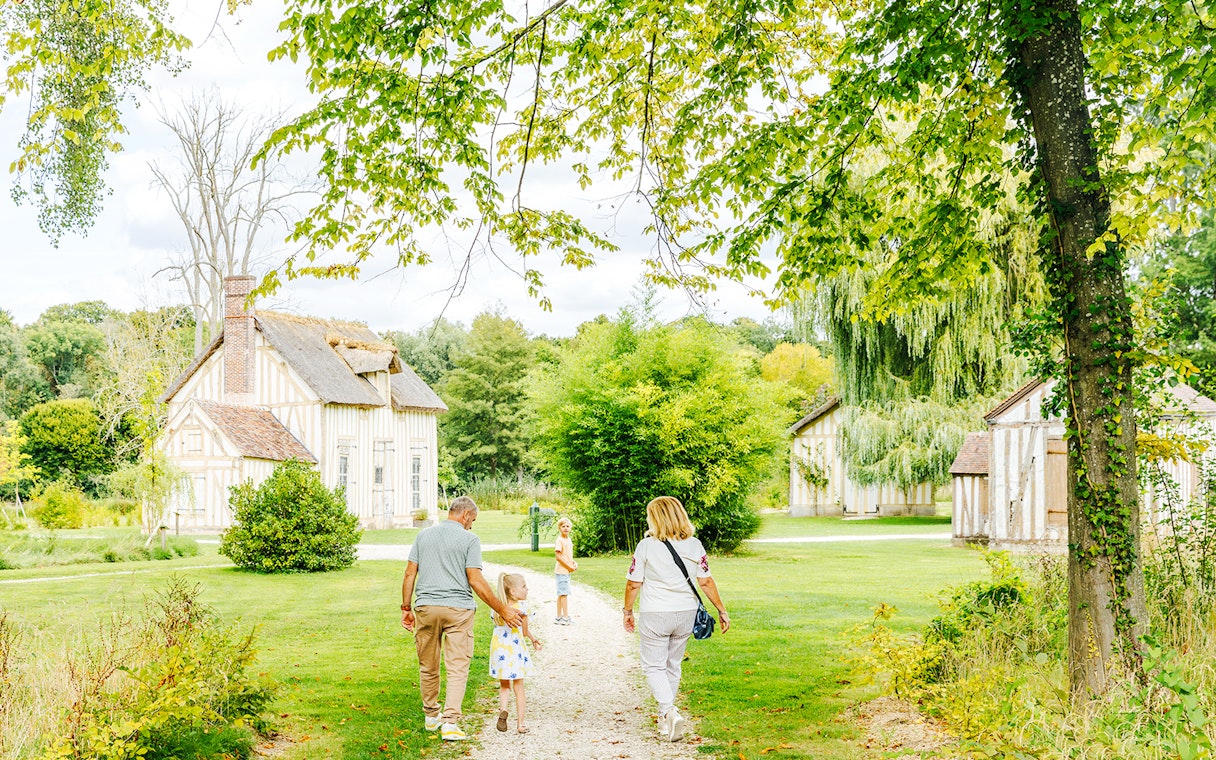 Family walking through gardens near Chateau of Chantilly, France.