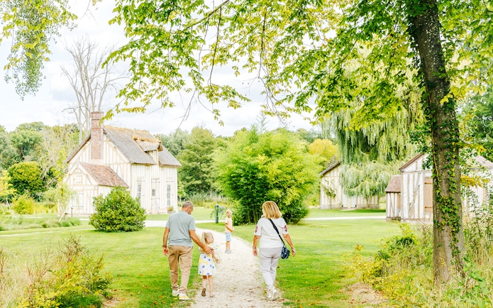 Family walking through gardens near Chateau of Chantilly, France.