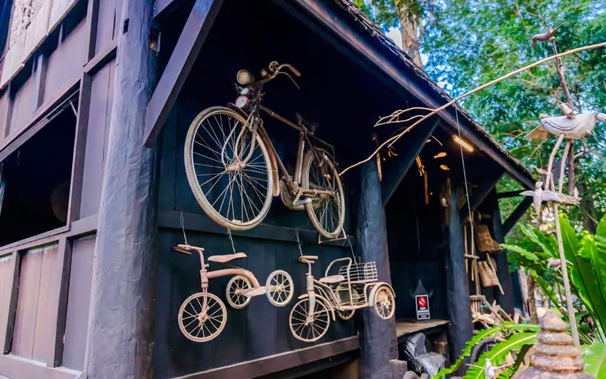 Bicycles and tricycles displayed on the wall of Black House (Baan Dam) in Thailand.