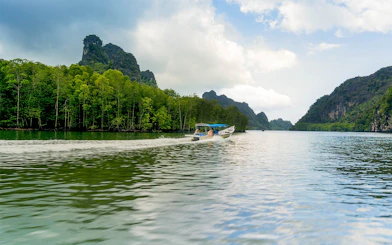 Speedboat cruising along the riverside of Kilim Park with lush greenery and rocky hills.